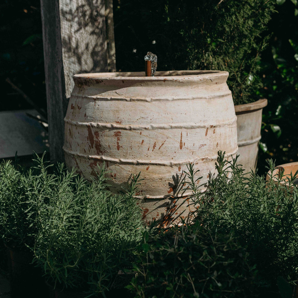 Ancient reclaimed Turkish terracotta fountain with gentle bubbling water feature in a garden setting.