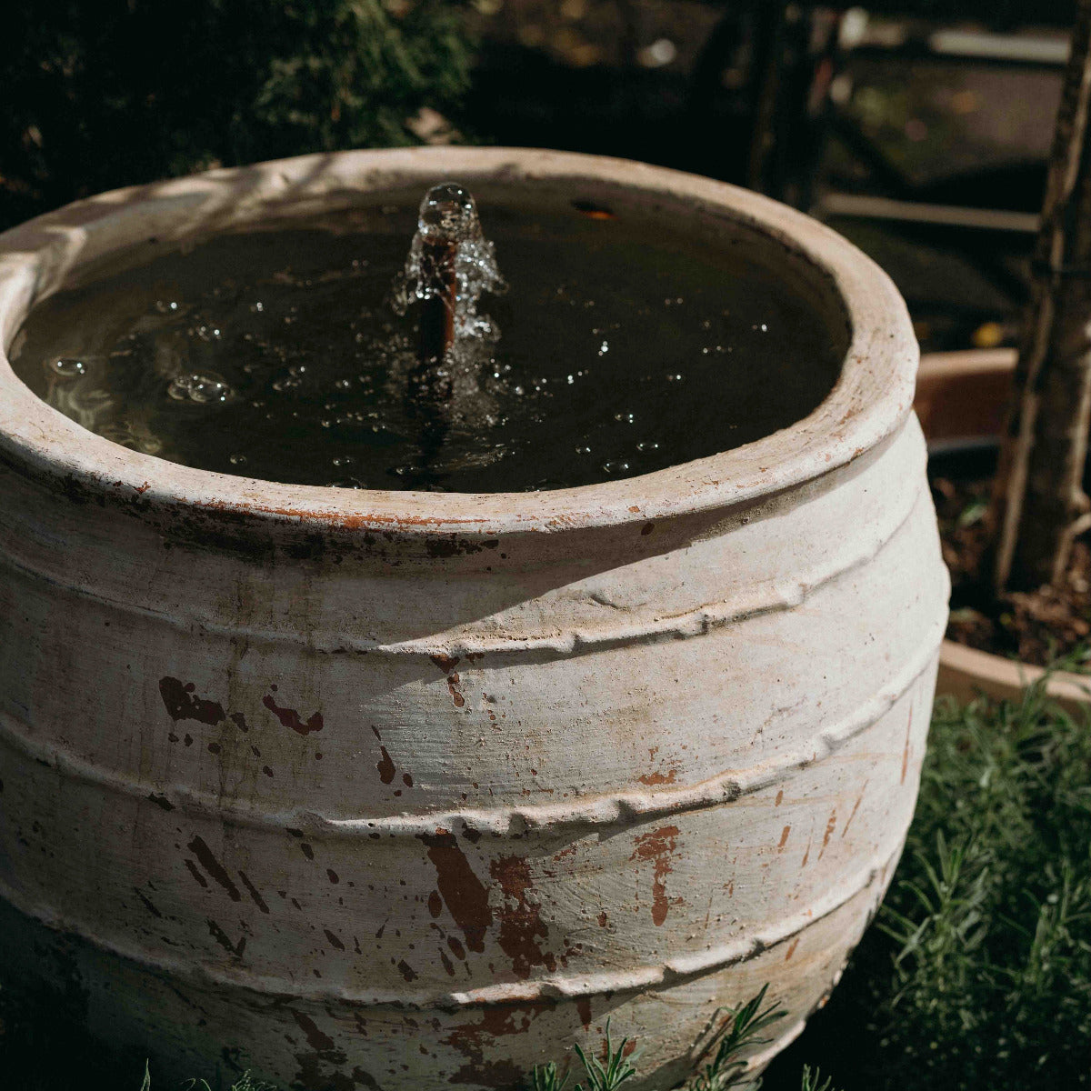 Ancient reclaimed Turkish terracotta fountain with gentle bubbling water feature in a garden setting.