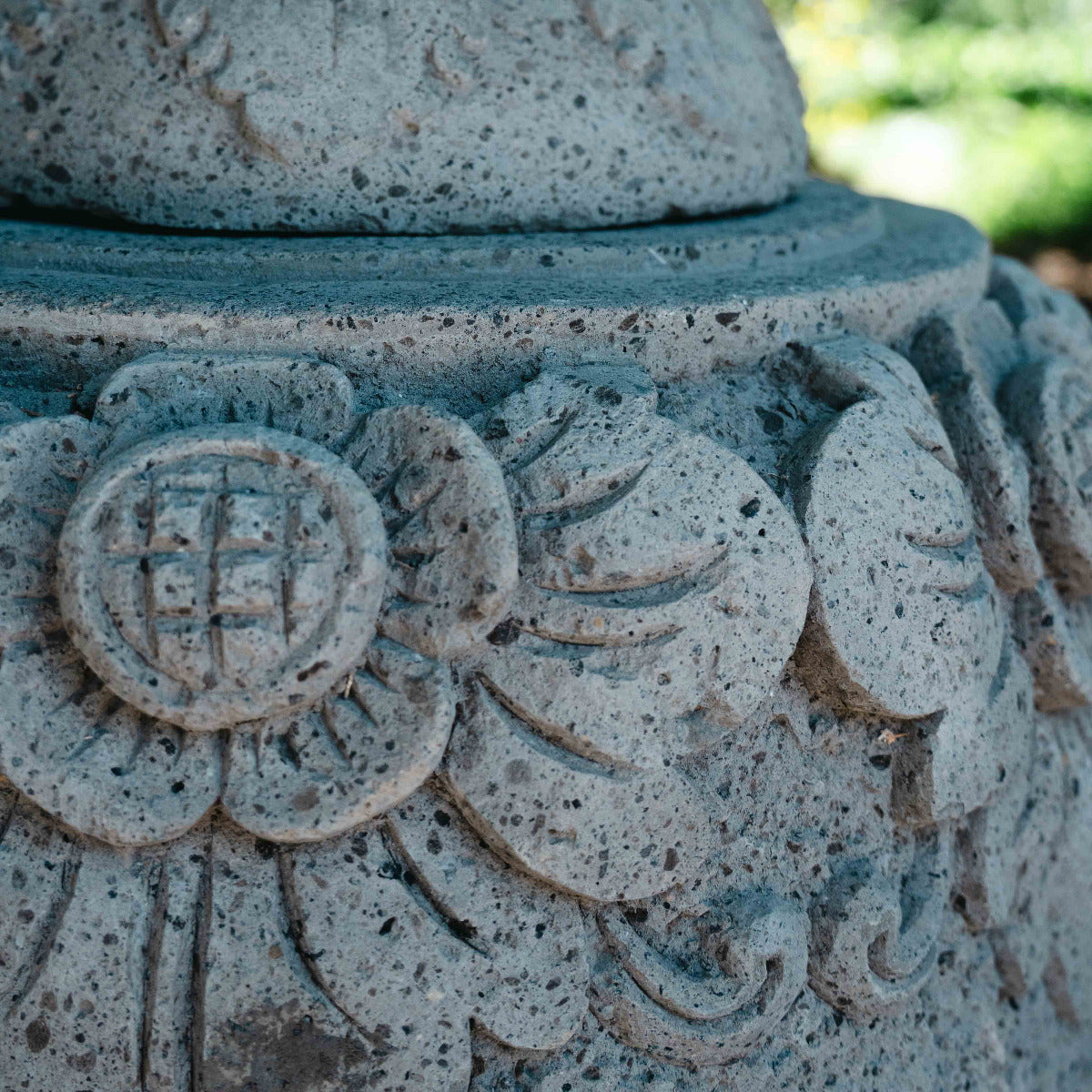 Close-up of a stone lantern with intricate carvings in a garden setting