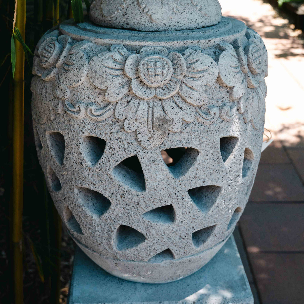 Decorative stone urn with intricate carvings in a garden setting