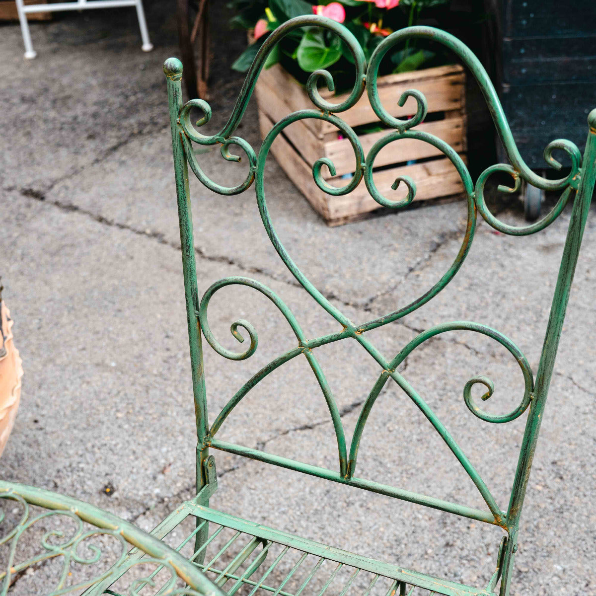 Wrought iron chair with decorative backrest on a concrete surface