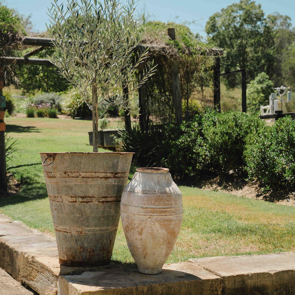 Two rustic vases on a stone ledge with a garden background