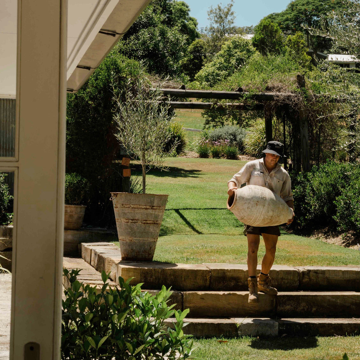Person carrying a large bag up a set of stone steps in a garden setting