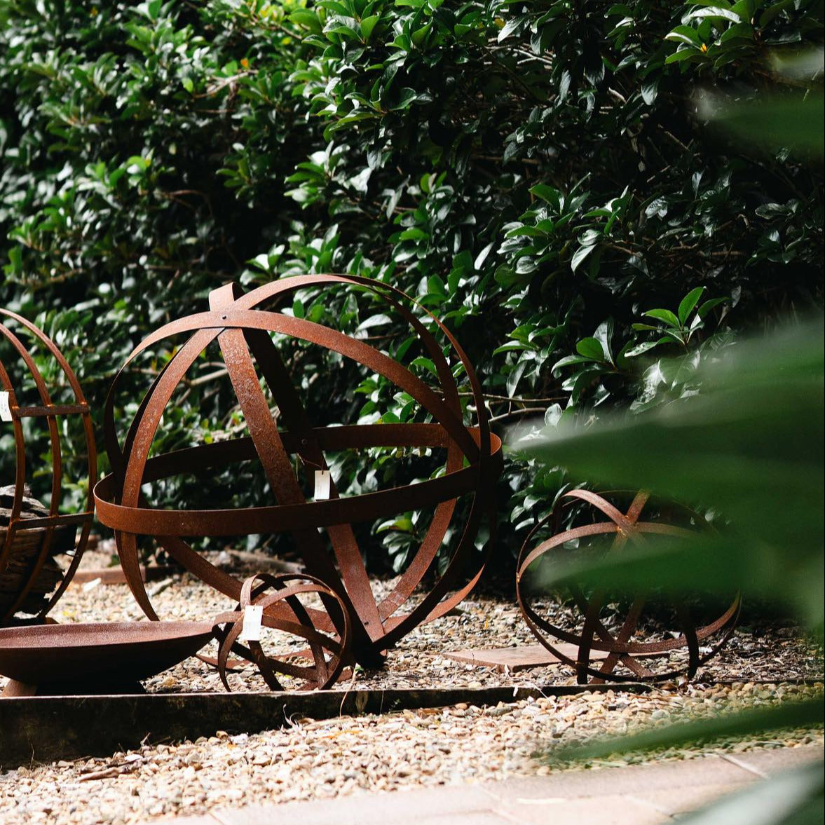 Large rusted steel Strappy Ball garden sculpture with open architectural design, available in 75cm and 100cm sizes.
