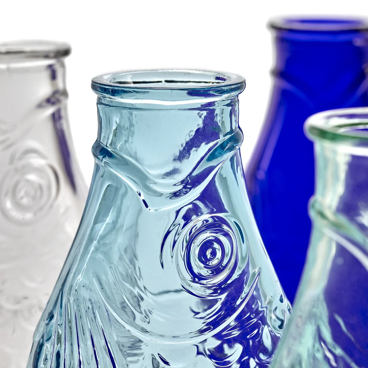 Close-up of clear glass bottles with textured design on a white background