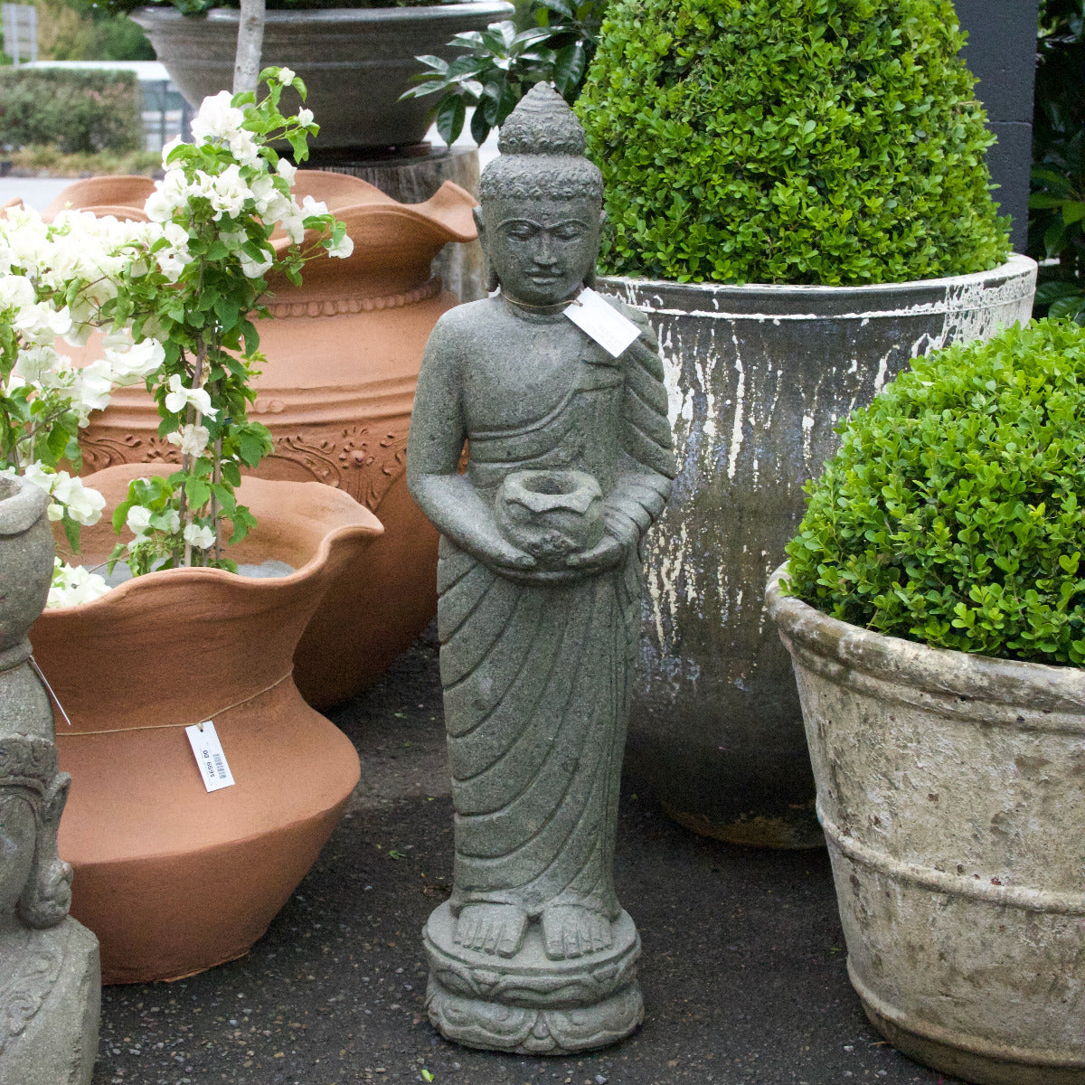 Stone statue of a Buddha figure among potted plants