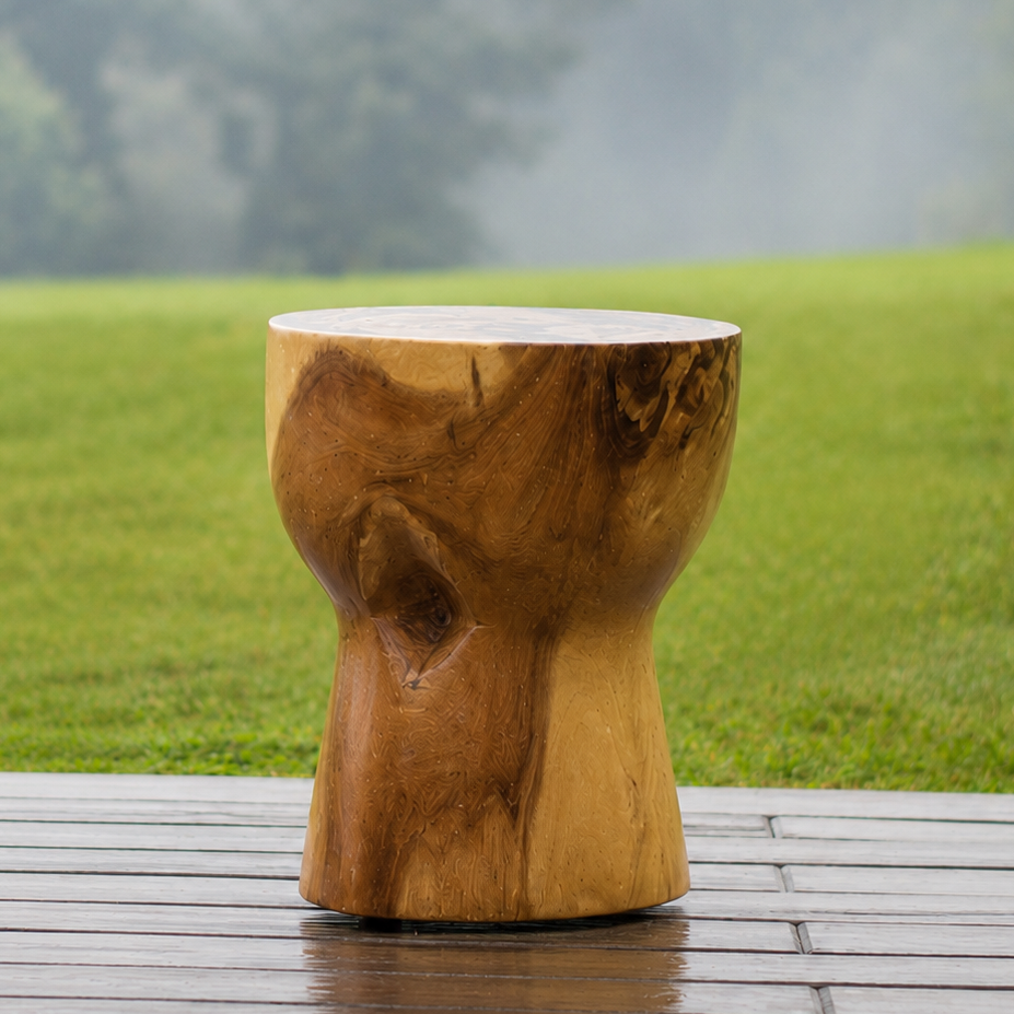 Wooden stool with natural texture on a wooden deck with a grassy field and trees in the background