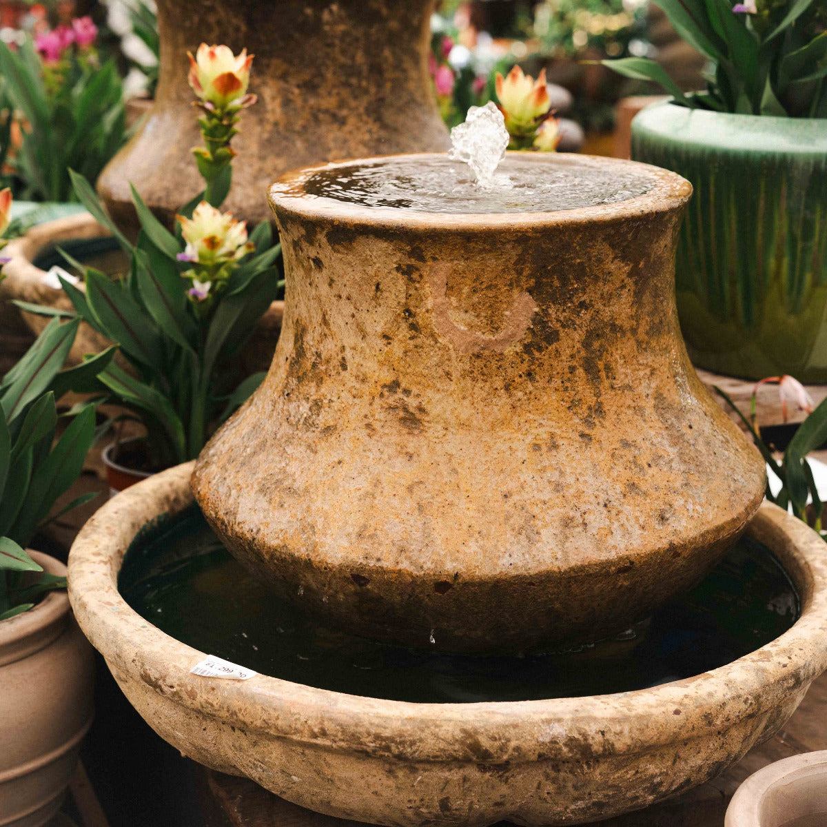 Decorative stone water fountain with plants in the background