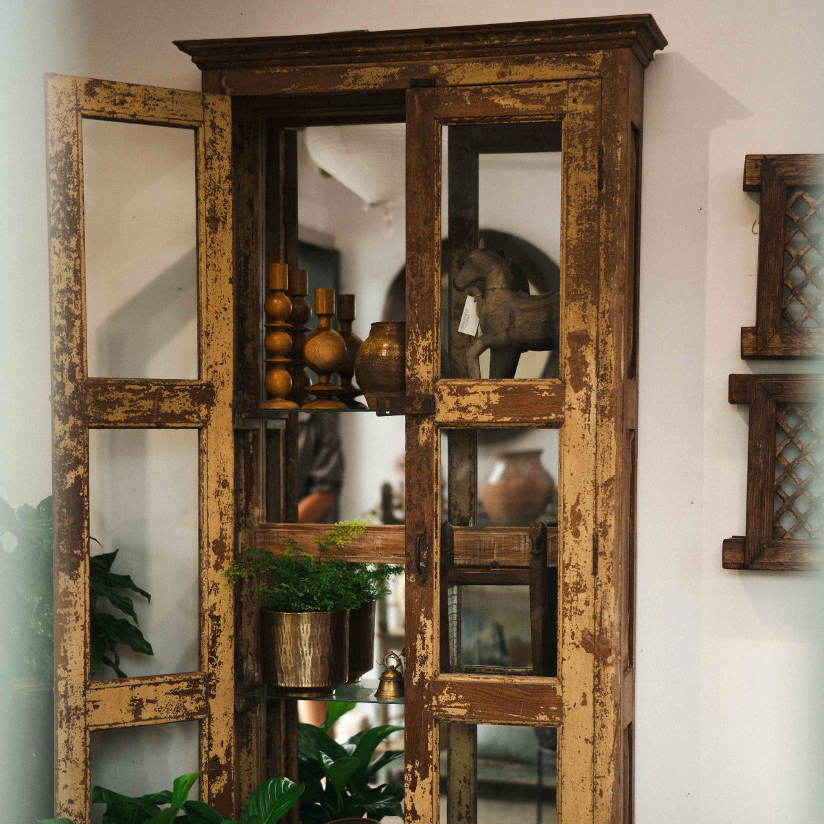 Vintage-style wooden cabinet with glass panels on a white wall.