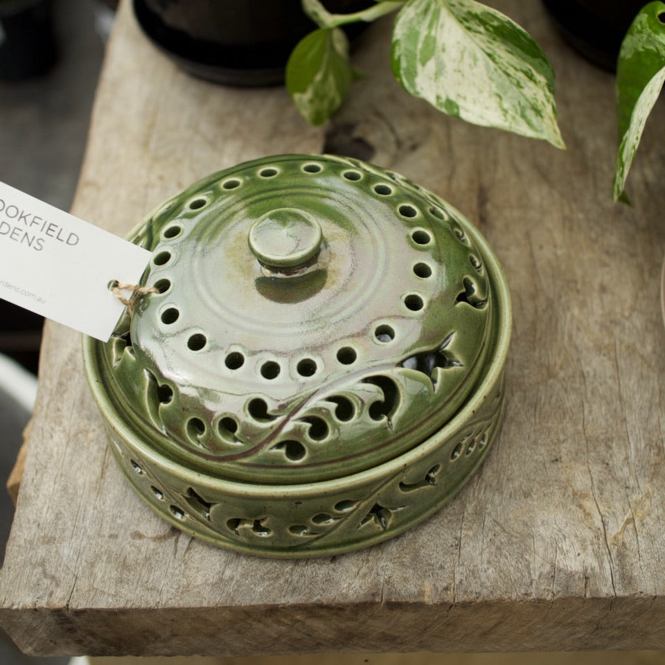 Green glazed ceramic mozzie coil holder with a decorative pierced lid for safely burning mosquito coils outdoors.
