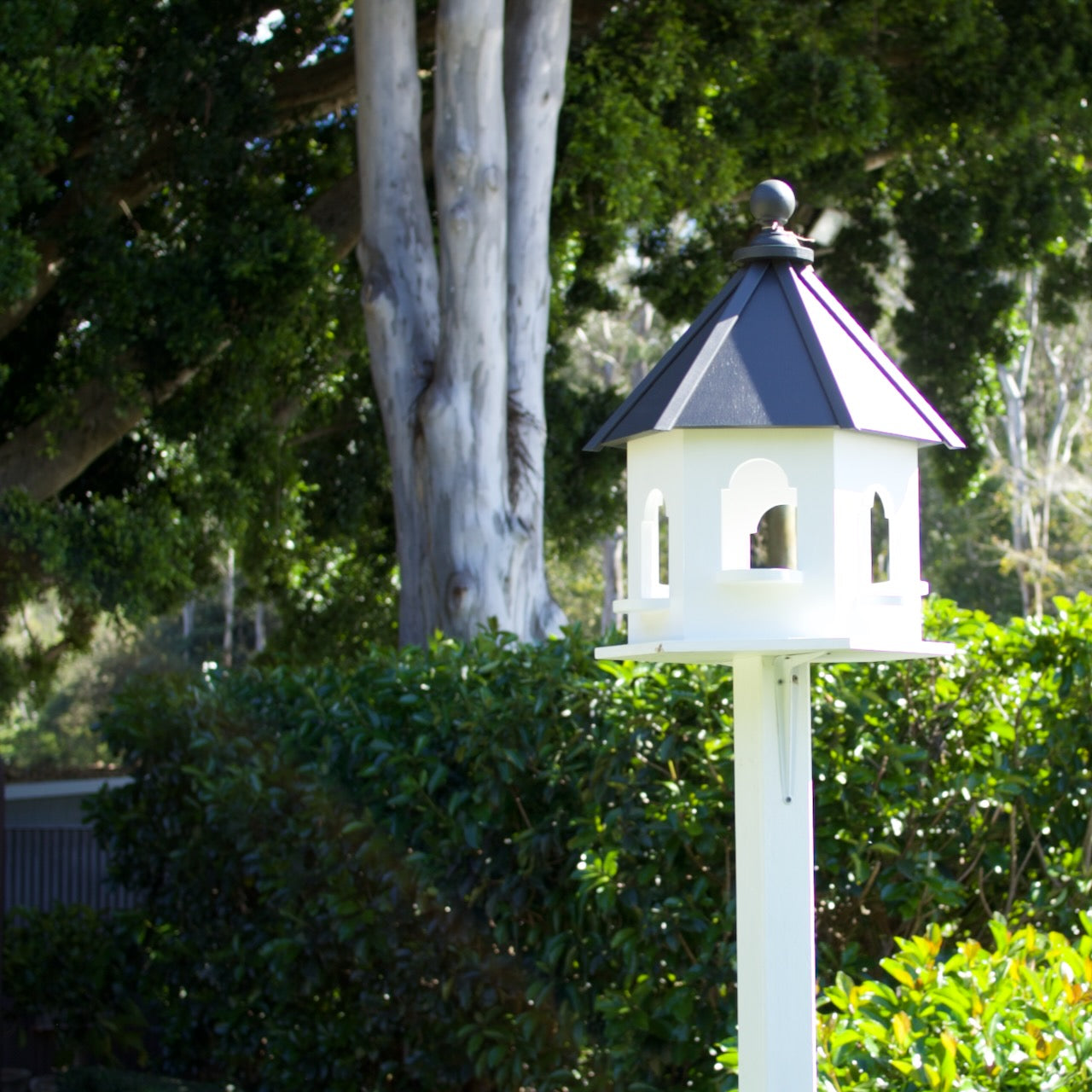 Elegant handmade white decorative dove cote in a lush Brisbane garden, mounted on a post as a timeless landscape feature.