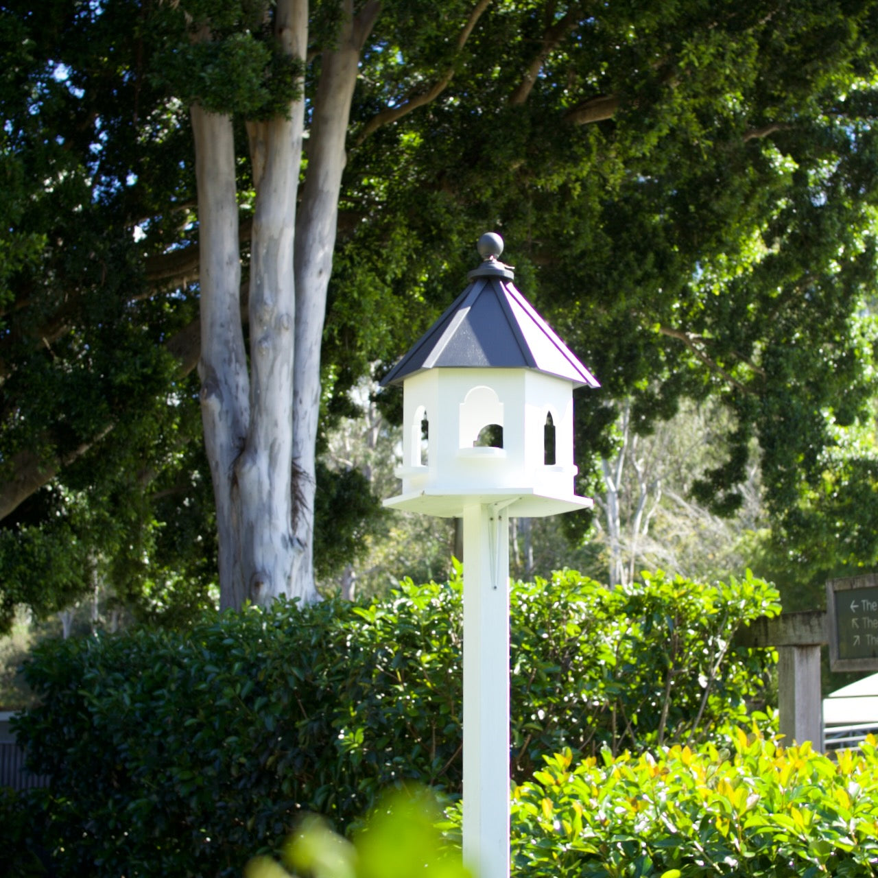 Elegant handmade white decorative dove cote in a lush Brisbane garden, mounted on a post as a timeless landscape feature.