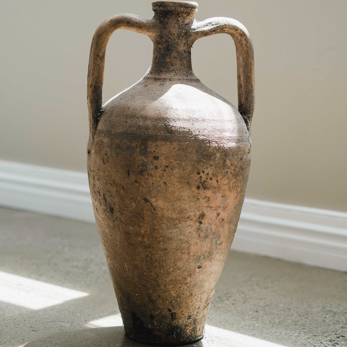 Hand painted Turkish amphora with twin handles and aged terracotta finish styled indoors