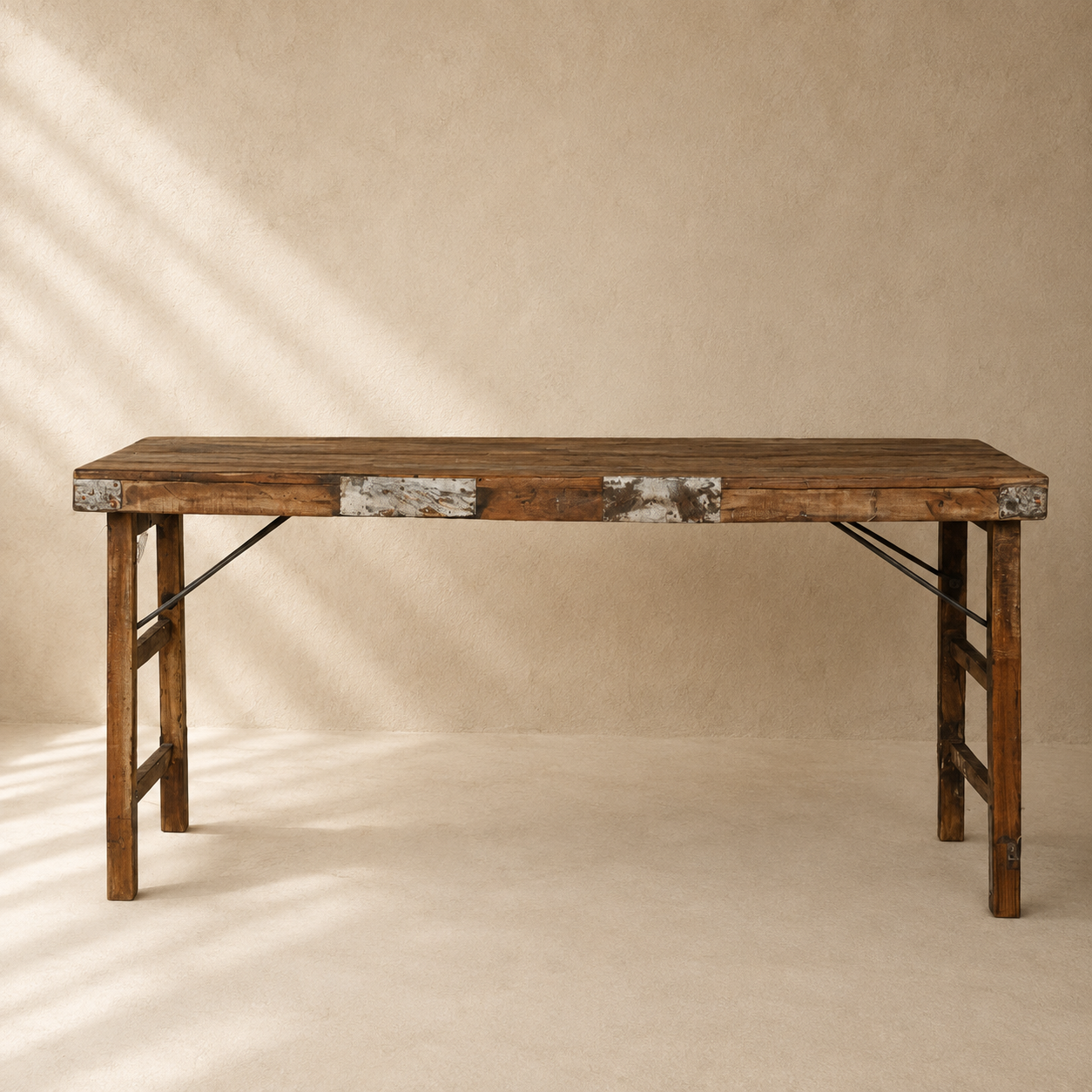 Long Indian wooden table with folding legs, aged timber top and rustic metal detailing, exclusive to Brookfield Gardens.