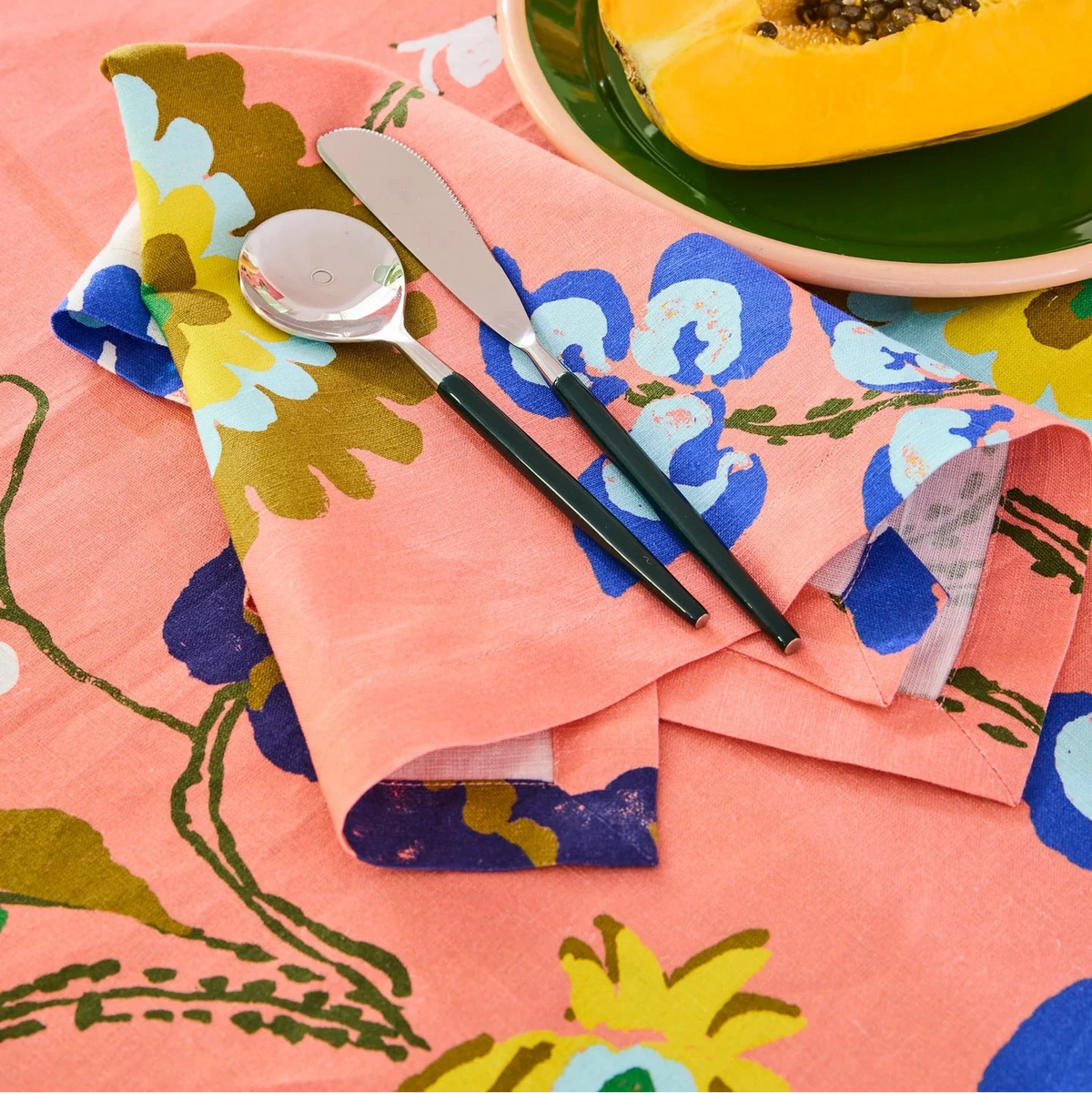Kip & Co x Anna Spiro Isabelle Sunset Tablecloth featuring oversized multicoloured florals on a coral pink background.