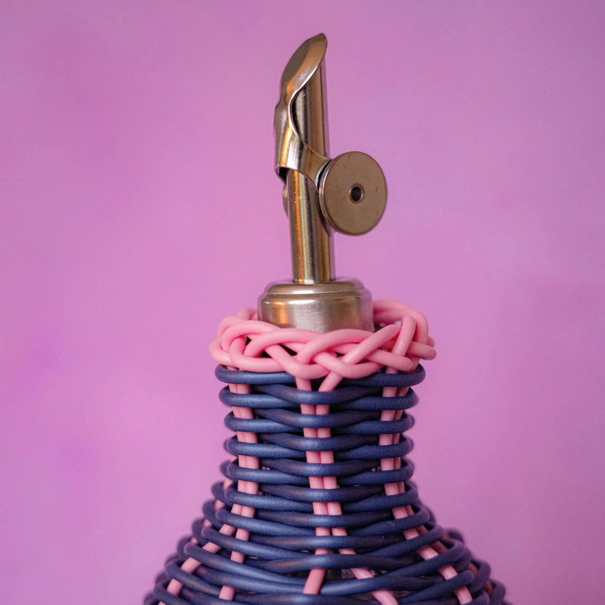 Maegen hand-woven oil pourer in navy with multicolour accents, faux rattan texture and stainless steel spout