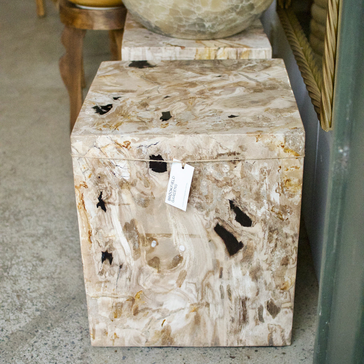 Marble-patterned side table with a price tag on a concrete floor.