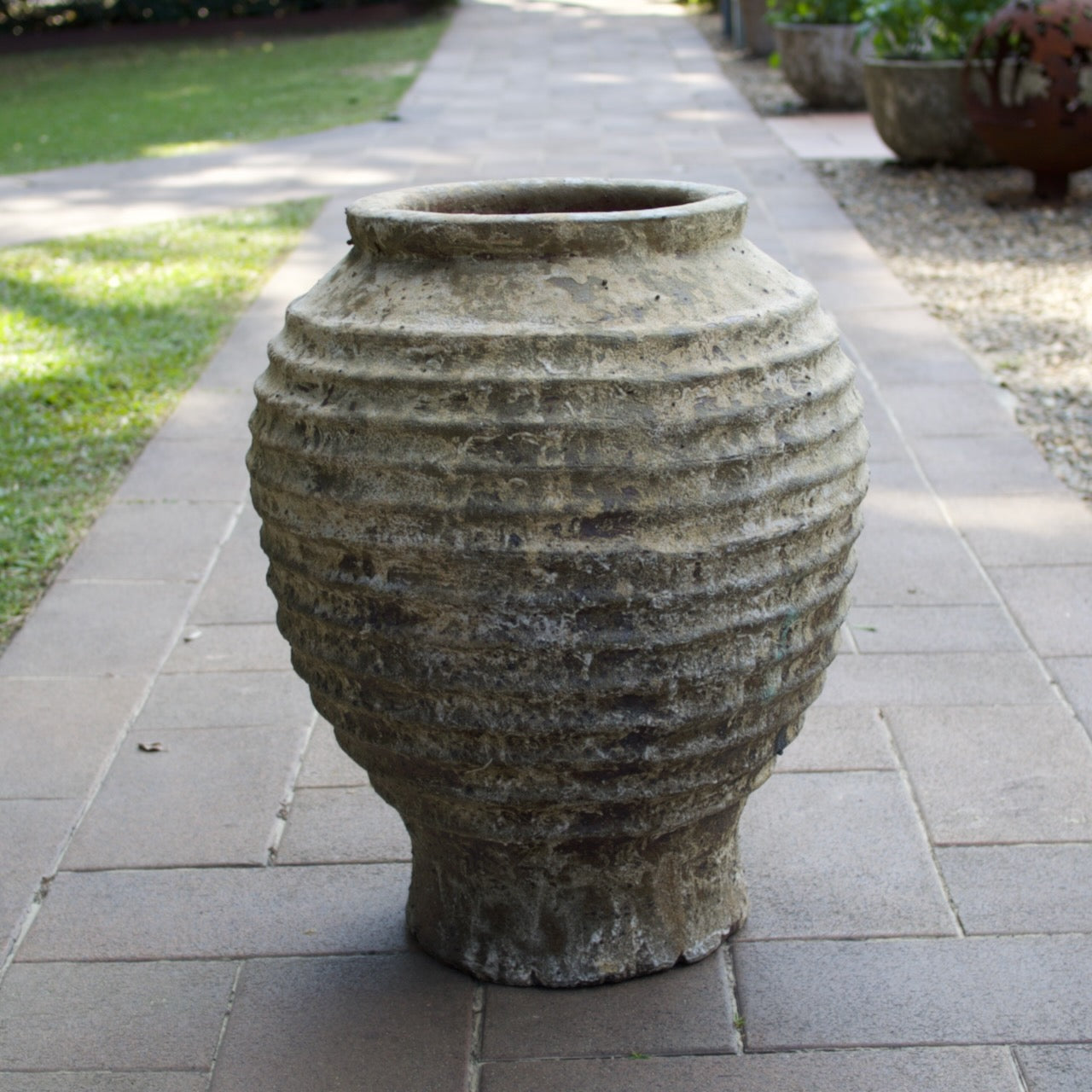 Rustica Bella Urn with a textured ribbed design and weathered antique finish, displayed as a Mediterranean-inspired feature planter at Brookfield Gardens, Brisbane.