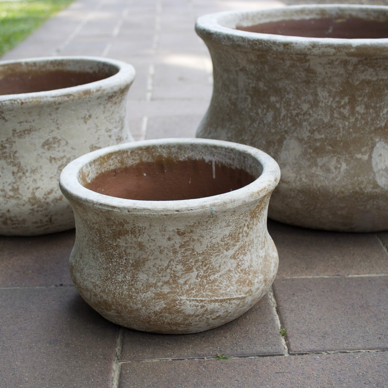 Rustica Low Lotus Pots in multiple sizes with a weathered antique finish, displayed as elegant feature pots at Brookfield Gardens, Brisbane.