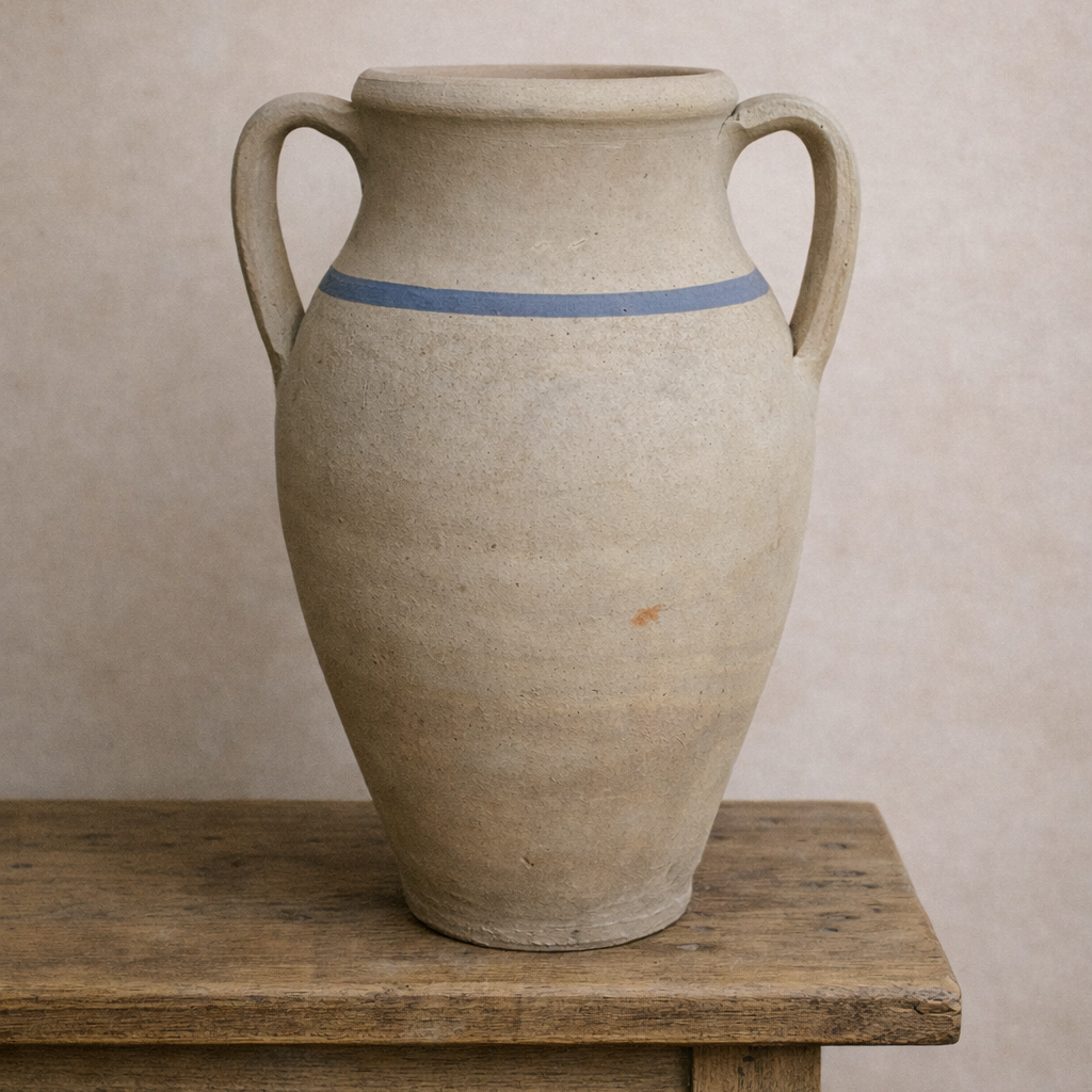 Aged Turkish terracotta urn with blue stripe and two handles, styled on a rustic timber table against a soft limewash wall.