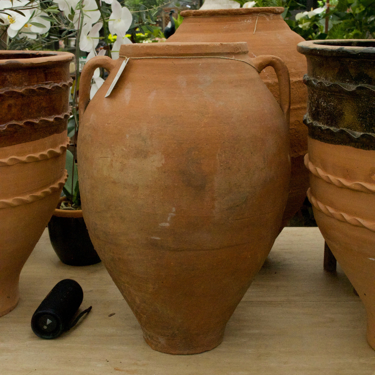 Terracotta pots on a wooden surface with a garden background