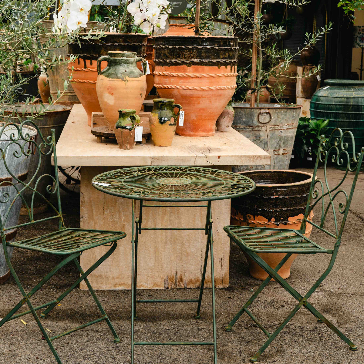 Outdoor setting with garden furniture and potted plants in a greenhouse.
