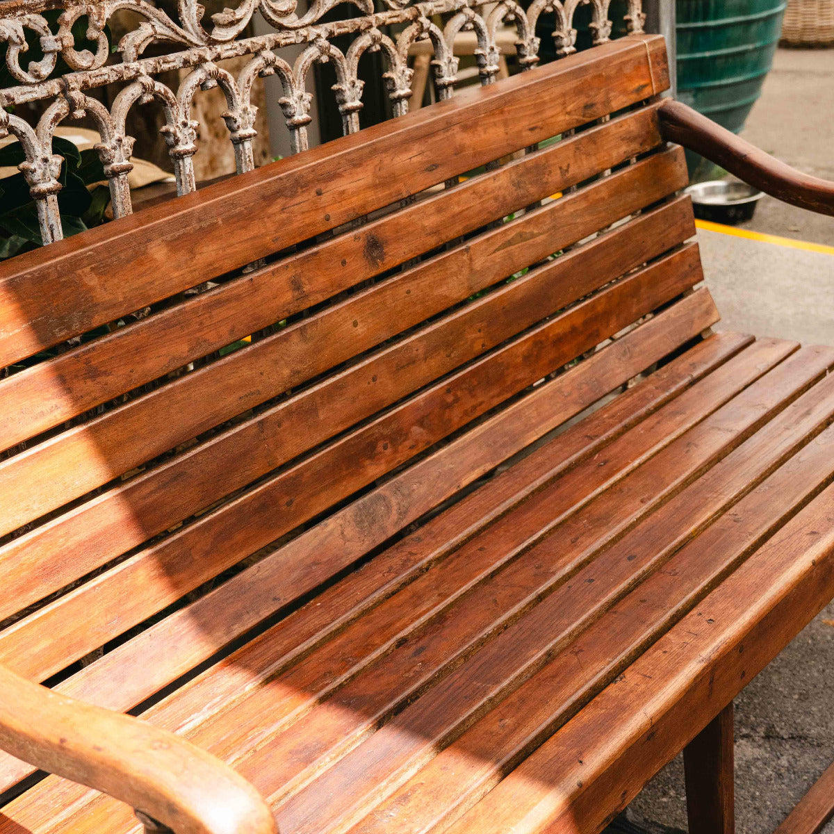 Wooden bench with ornate metal backrest on a sunny day