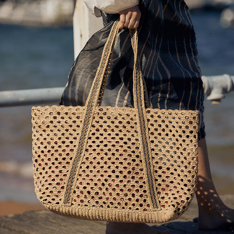 Person holding a woven bag by a waterfront