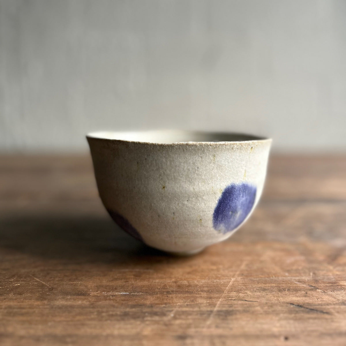 Ceramic bowl with a blue speck on a wooden surface