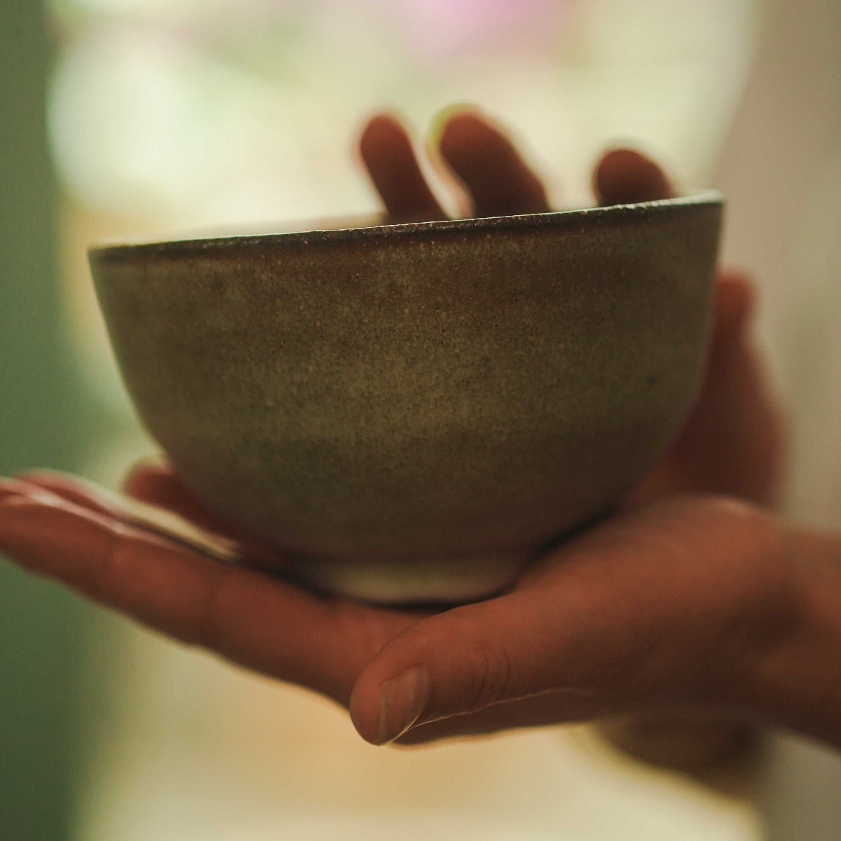 Hand holding a ceramic bowl with a blurred background