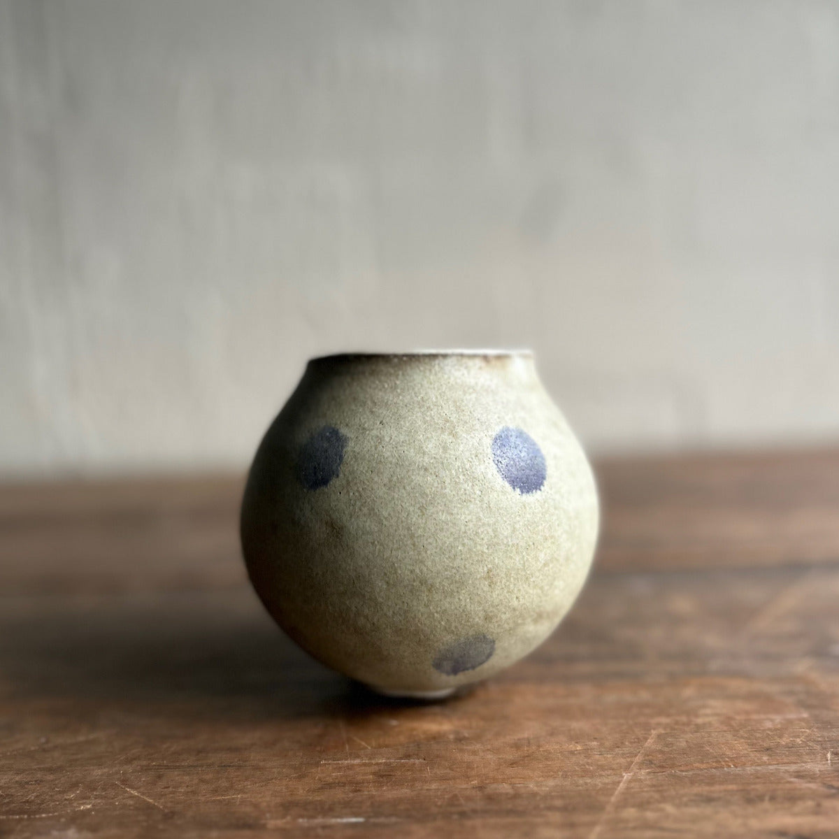 Small ceramic vase with speckled design on a wooden surface