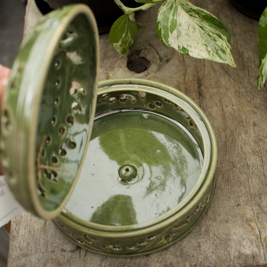 Green glazed ceramic mozzie coil holder with a decorative pierced lid for safely burning mosquito coils outdoors.