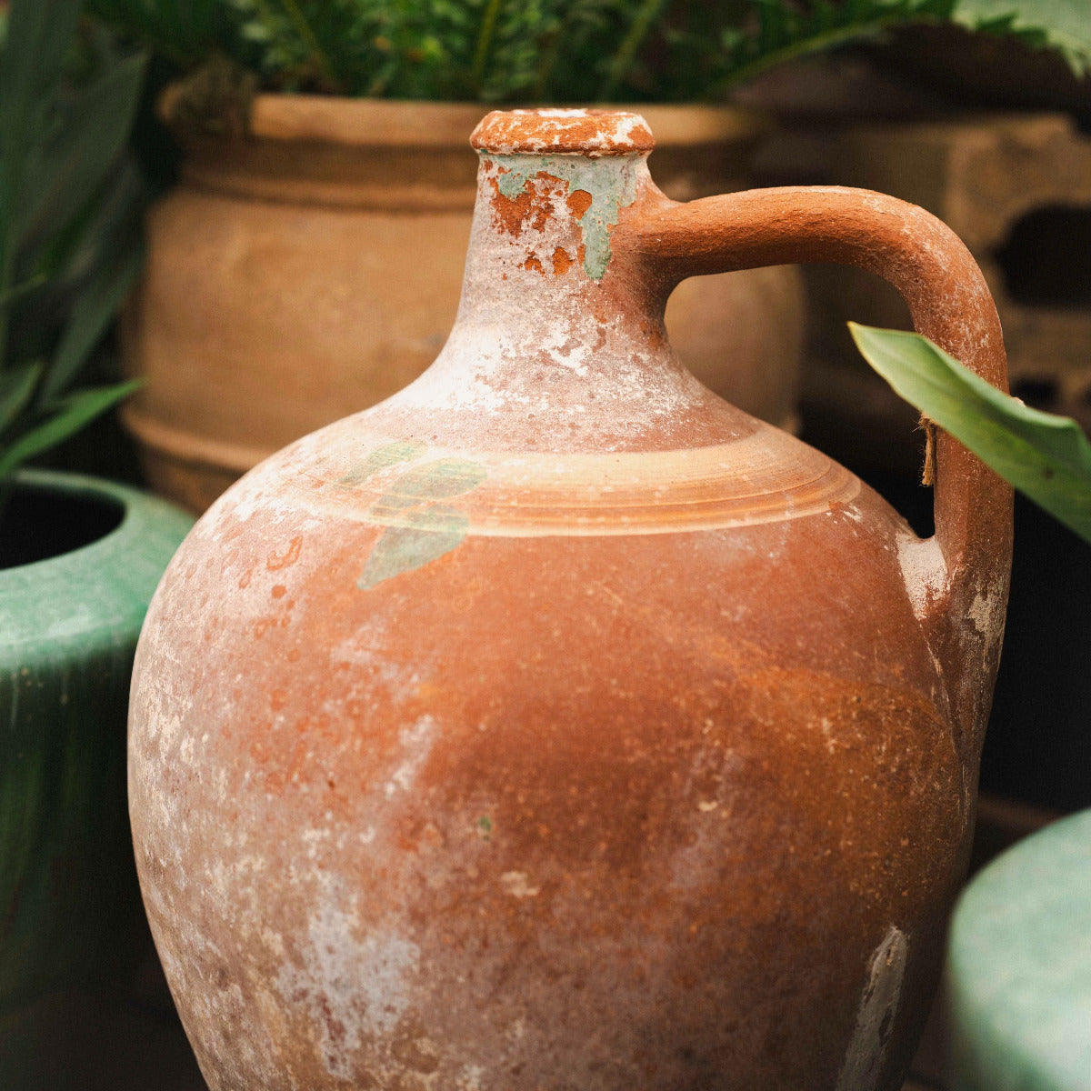 Terracotta jar with a handle in a garden setting