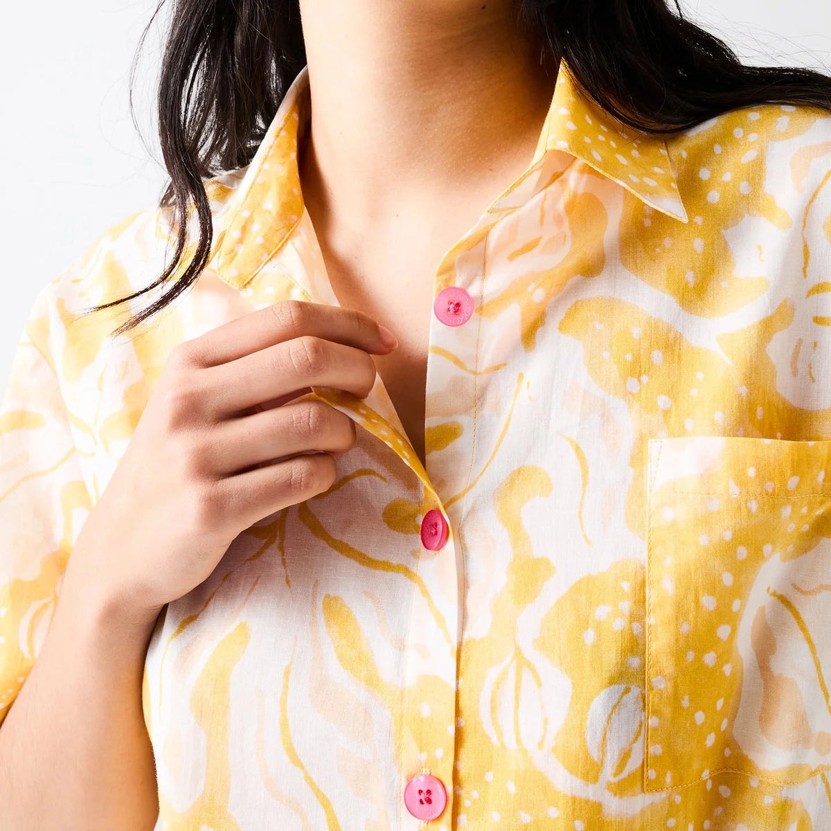 Kip & Co x Anna Spiro Elsternwig Fig organic cotton pyjama set featuring a yellow and cream patterned short-sleeved shirt with pink buttons and matching full-length pants.