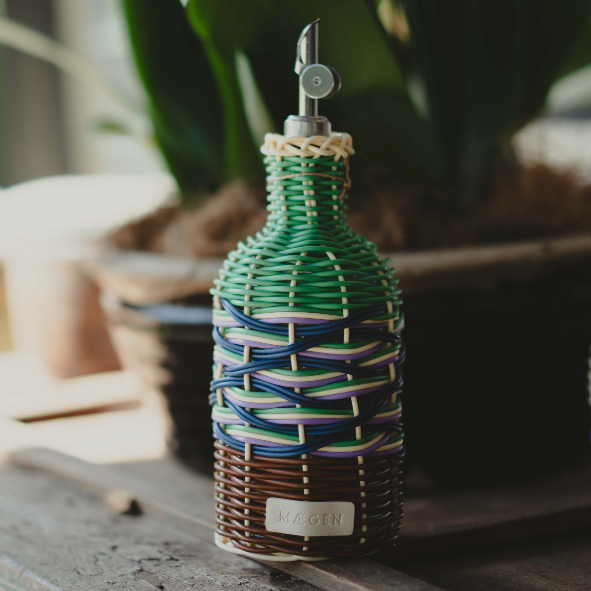 Decorative bottle with woven design and 'Ninogen' label on a wooden surface.
