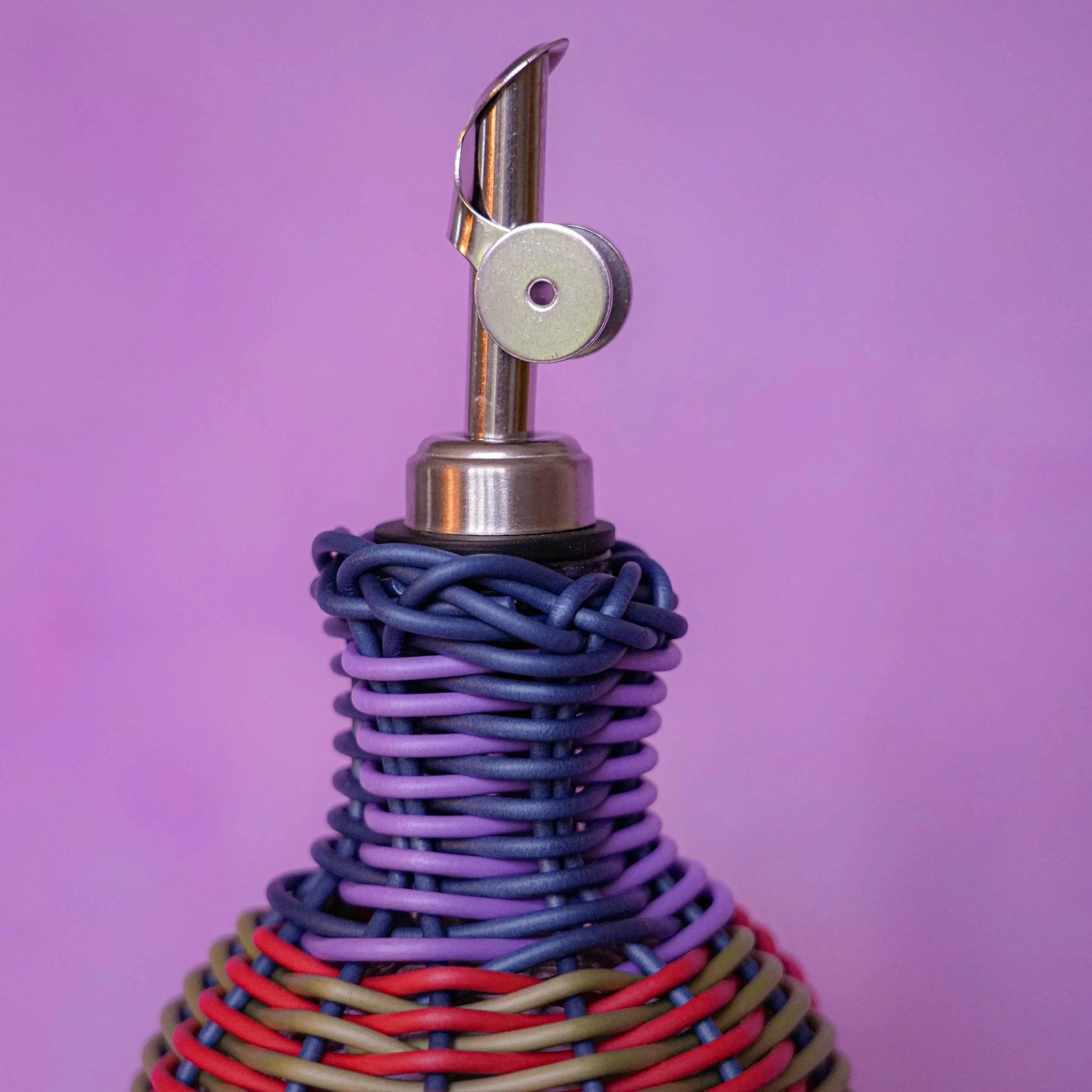 Maegen hand-woven oil pourer in navy with multicolour accents, faux rattan texture and stainless steel spout