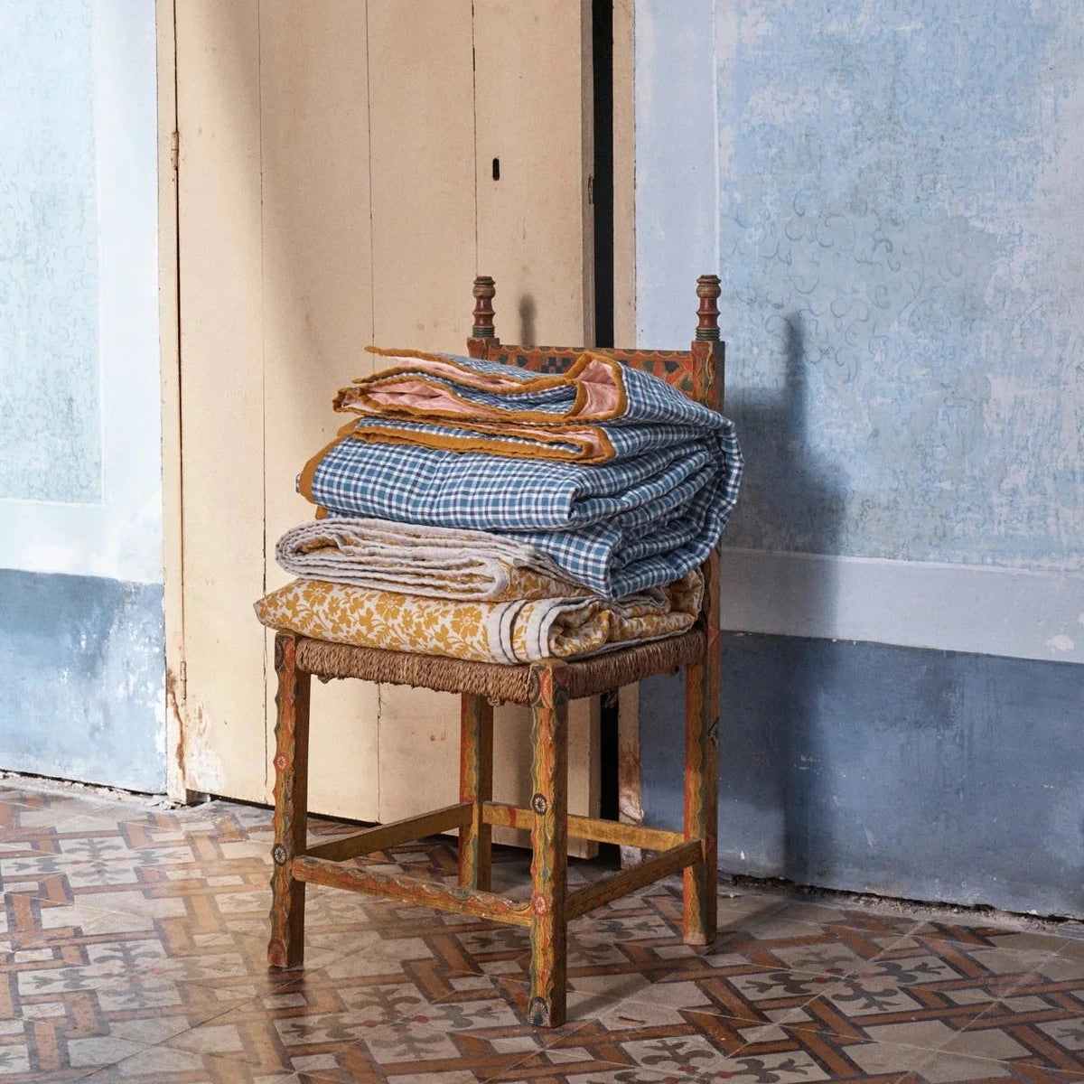 Cefalù Pesca double-sided linen quilt draped over bed, soft textured fabric in warm reversible tones styled in a relaxed bedroom setting