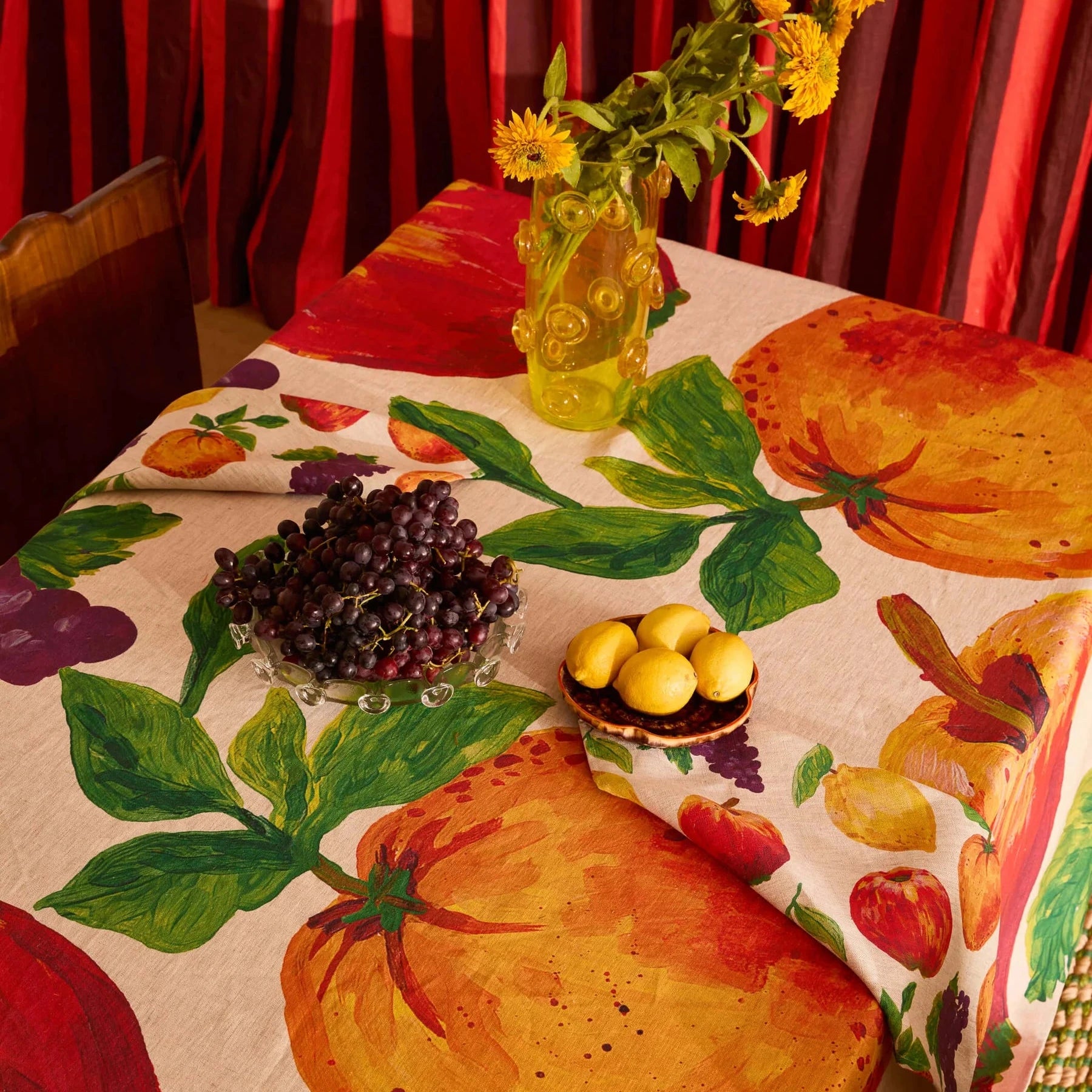 Tablecloth with fruit and vegetable pattern on a table with decorative elements.