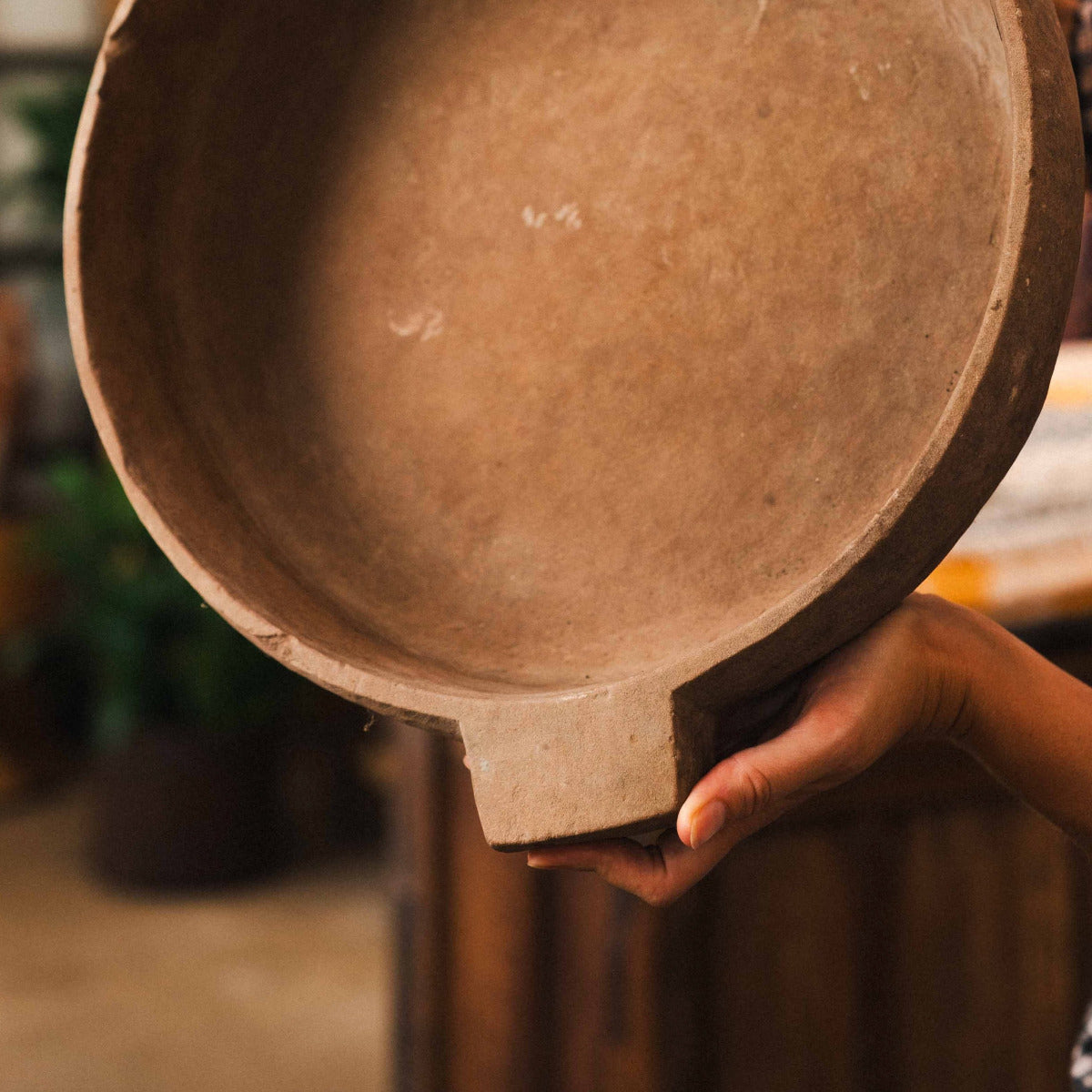 Terracotta low shallow bowl with wide rim and architectural side tabs, styled indoors.