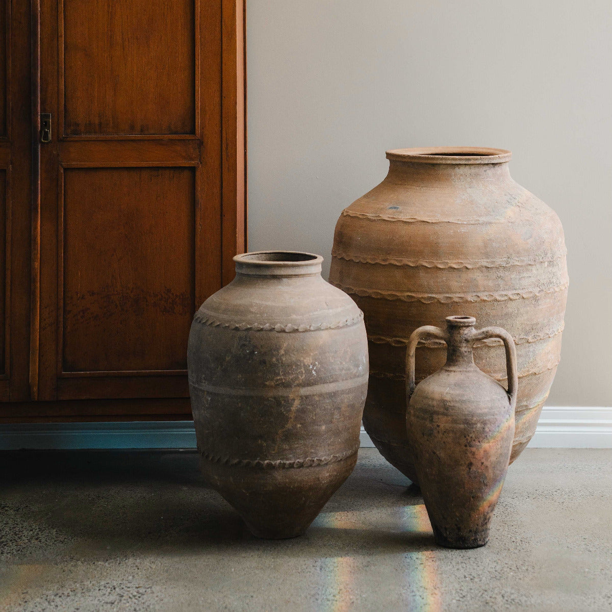 Hand painted Turkish amphora with twin handles and aged terracotta finish styled indoors