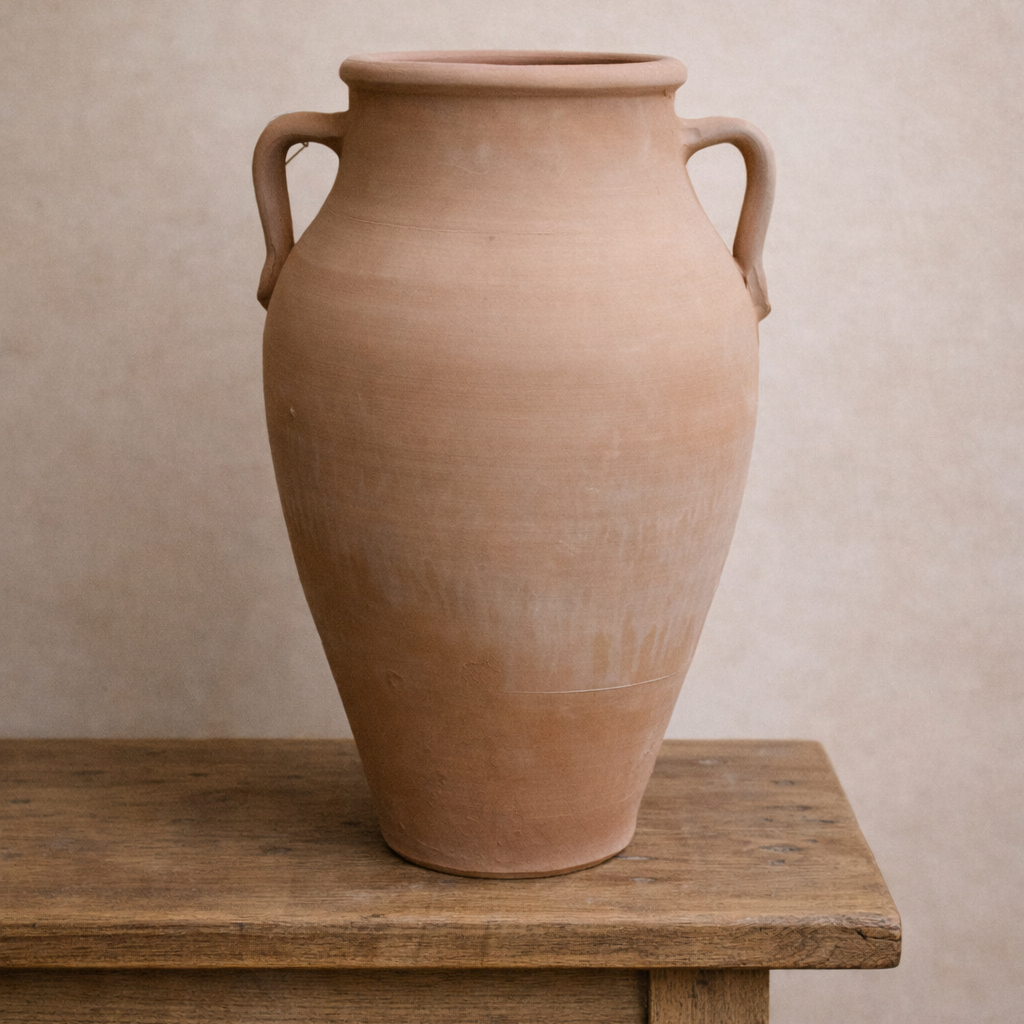 Handcrafted Turkish terracotta jar with two handles and classical amphora shape, displayed on a rustic table.