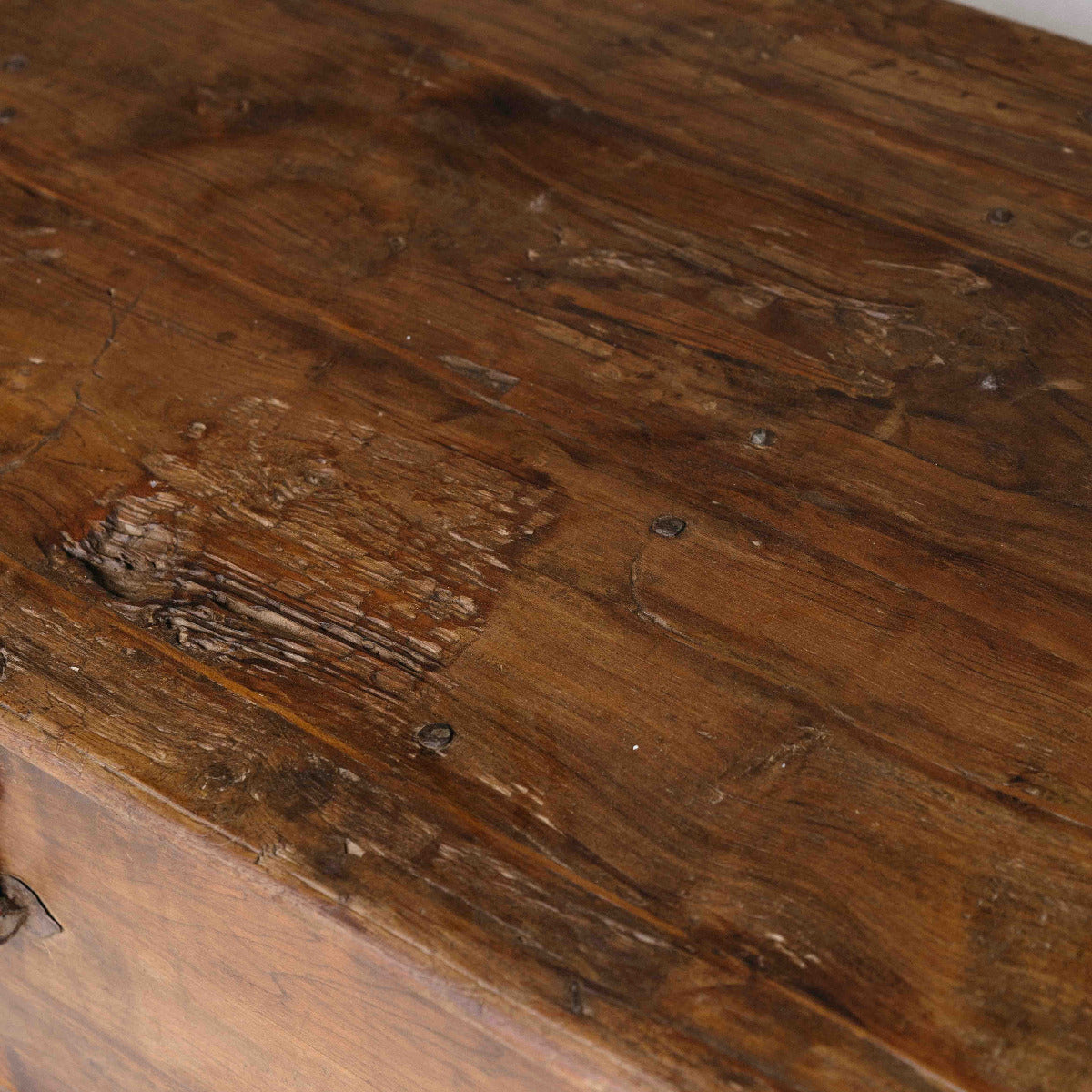 Close-up of a rustic dark brown wooden surface showing natural grain, knots, and weathered texture.