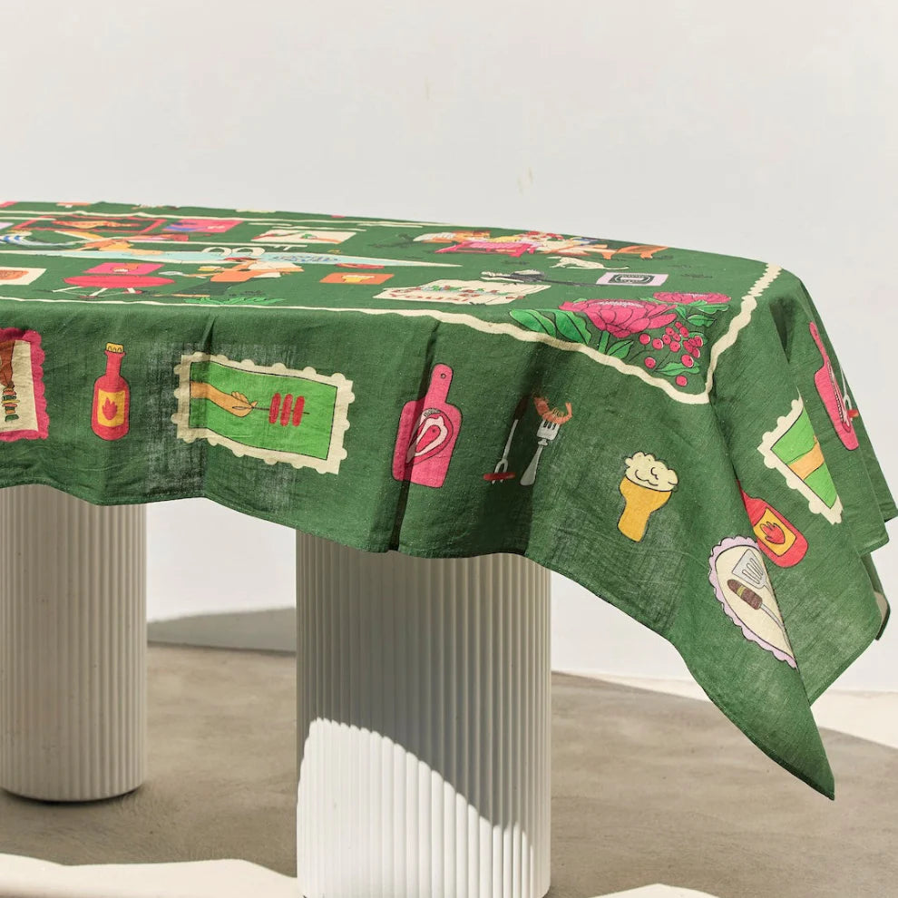 Warm Weekend tablecloth with green background and playful illustrated food and drink motifs.