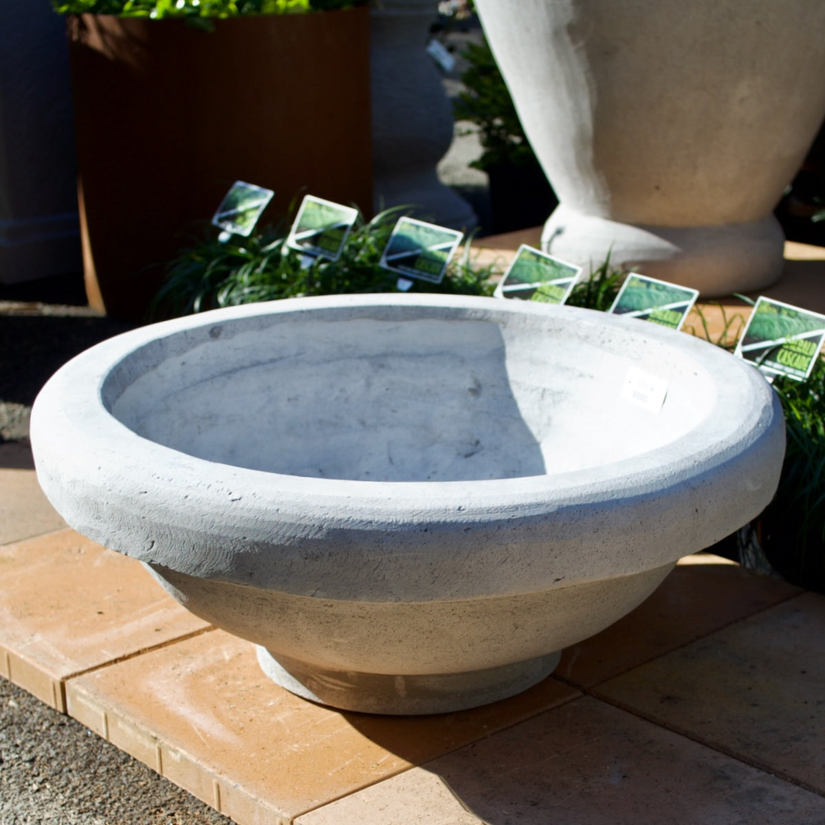 Grey stone-look garden water bowl with wide rounded edge and low circular profile.