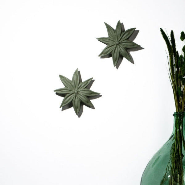 Decorative green star-shaped objects on a white background with a green vase.