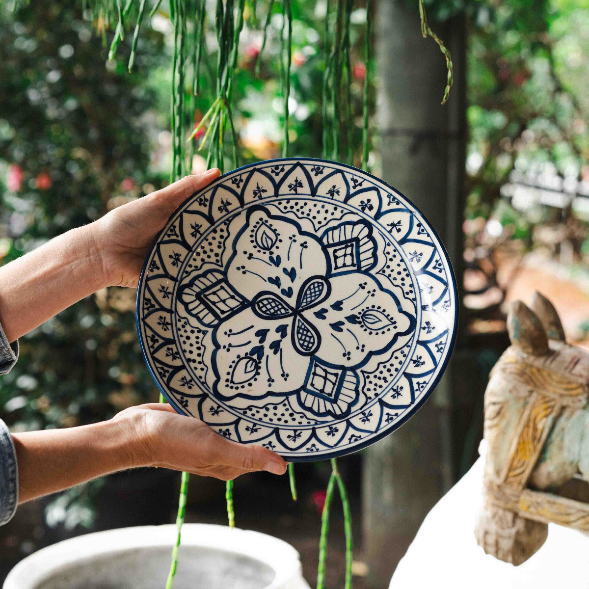 Blue and white patterned Karlie plate with intricate floral motif held outdoors in garden setting