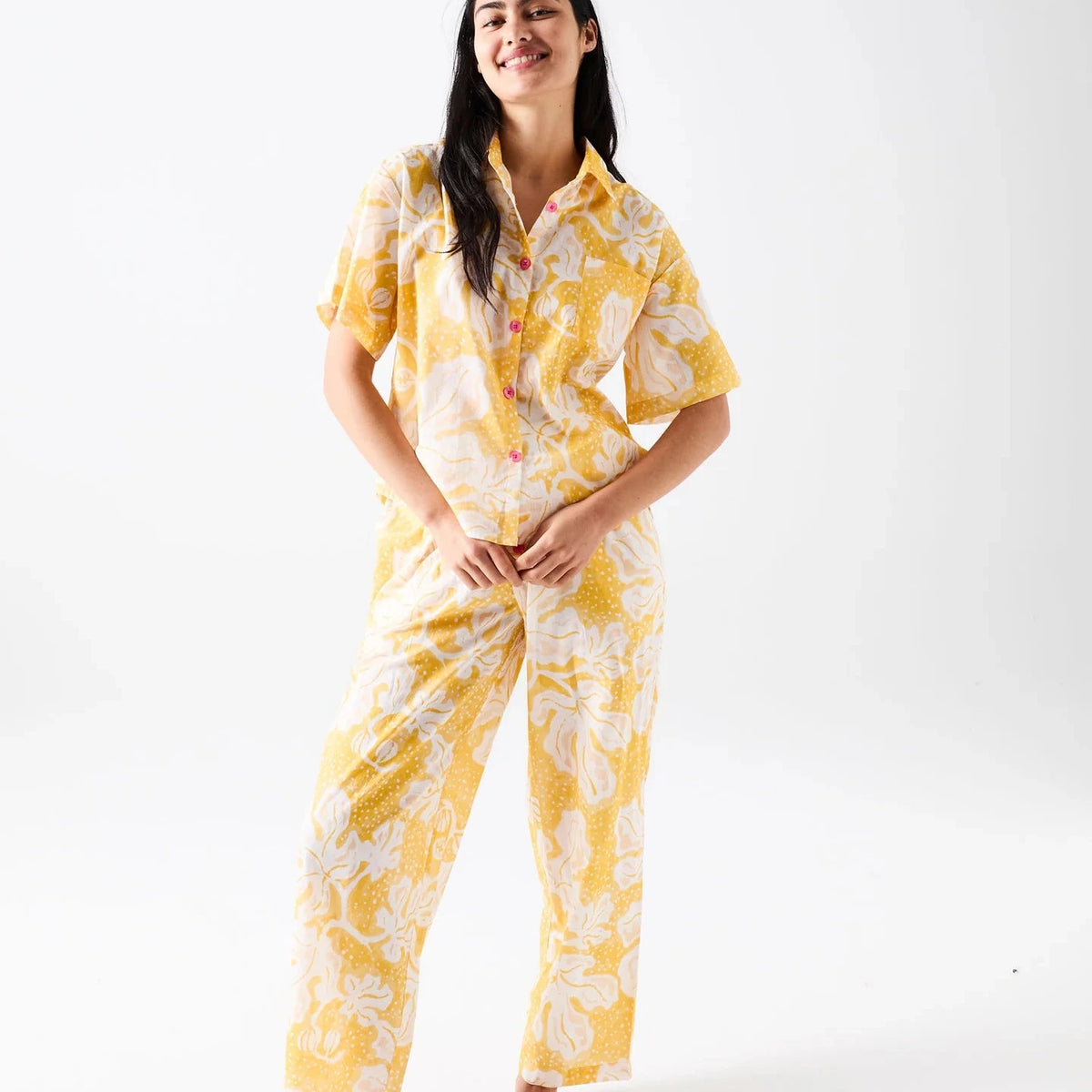 Kip & Co x Anna Spiro Elsternwig Fig organic cotton pyjama set featuring a yellow and cream patterned short-sleeved shirt with pink buttons and matching full-length pants.