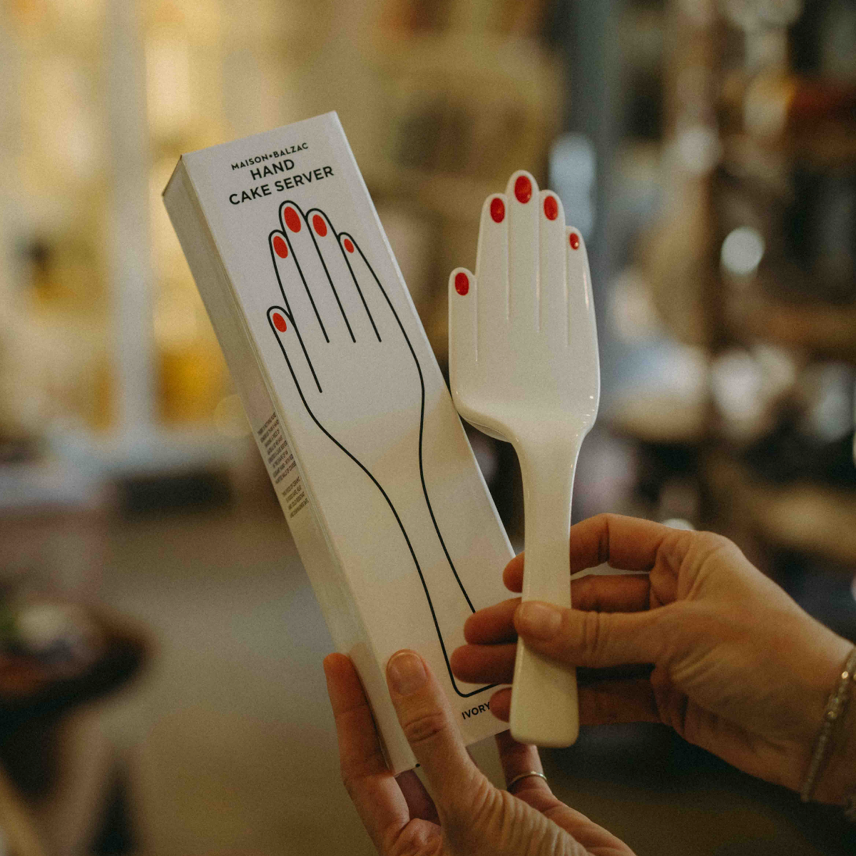Maison Balzac ivory glazed ceramic hand-shaped cake server with glossy red fingernails.