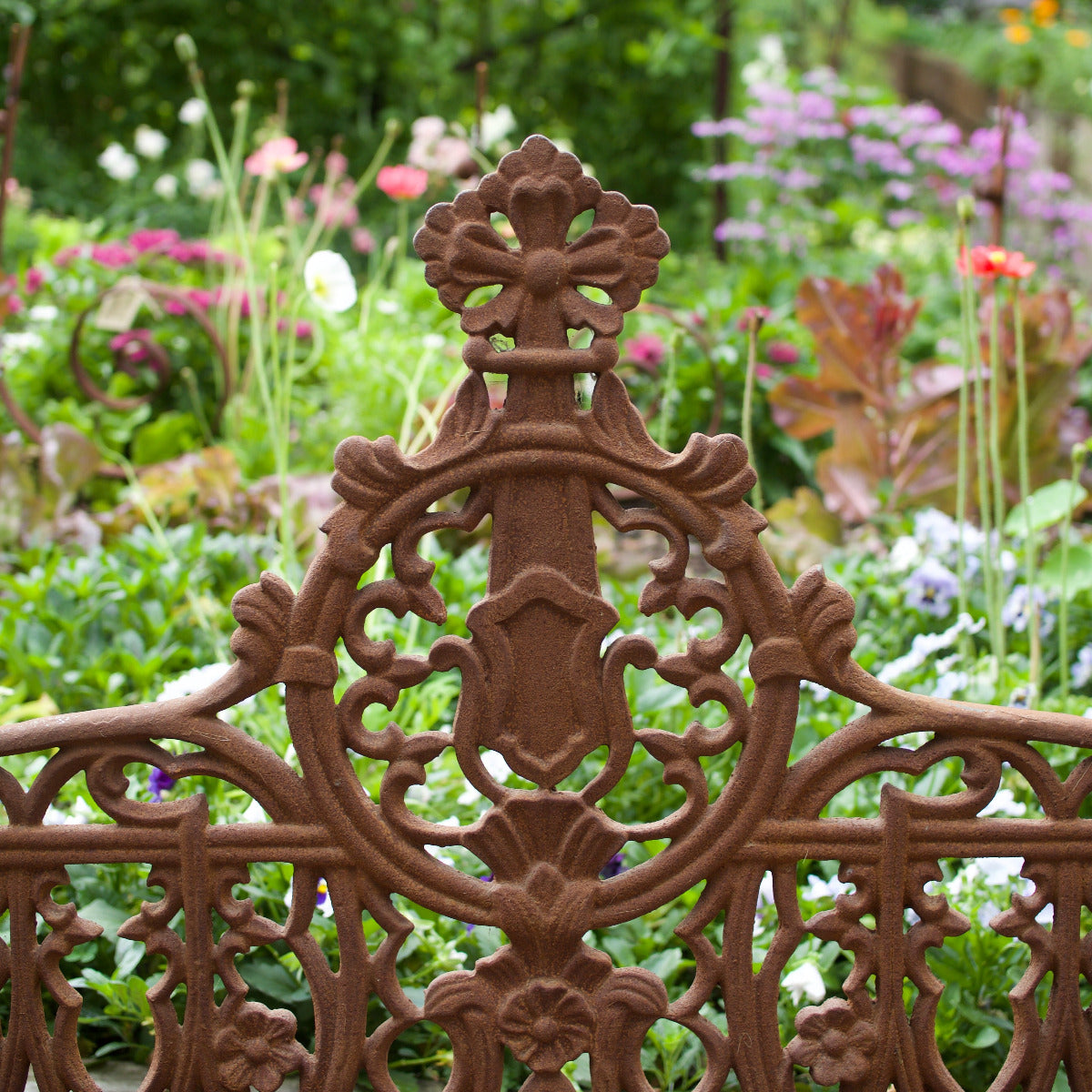 ornate Shelly garden bench with decorative detailing displayed amongst lush flowering plants at Brookfield Gardens Brisbane.