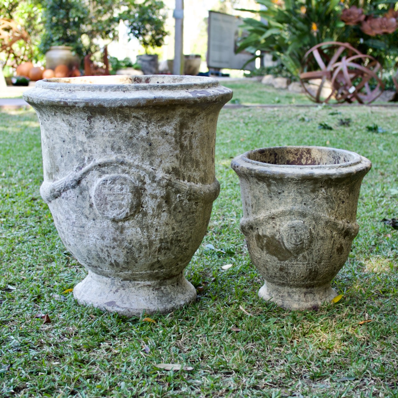 Rustica Anduze urns in two sizes with a weathered antique finish, displayed as elegant French-inspired feature pots at Brookfield Gardens, Brisbane.